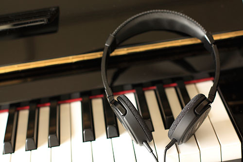 Headphones resting on a piano keyboard, silent piano system