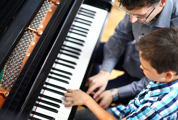 Piano teacher working with a student at an upright piano
