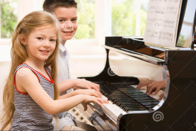 Children sitting at a piano smiling