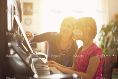 Piano teacher working with a student at an upright piano