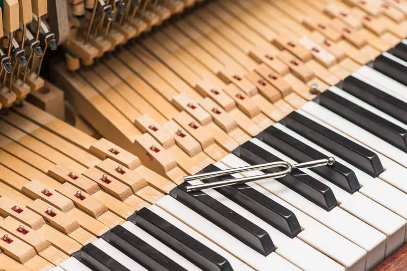 Image of a piano being repaired and tumed