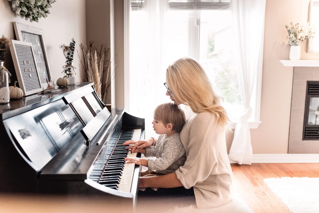 Woman with her child on her lap playing their rental piano in New York City apartment