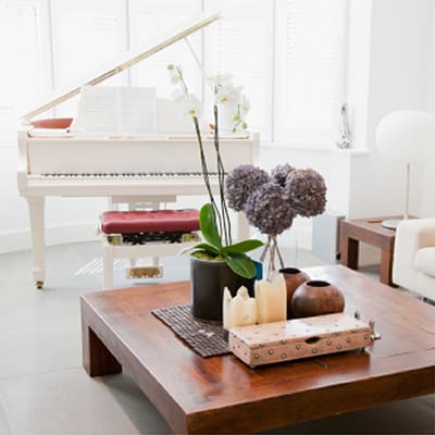 Real estate and staging piano rental in back of a coffee table with flowers and books