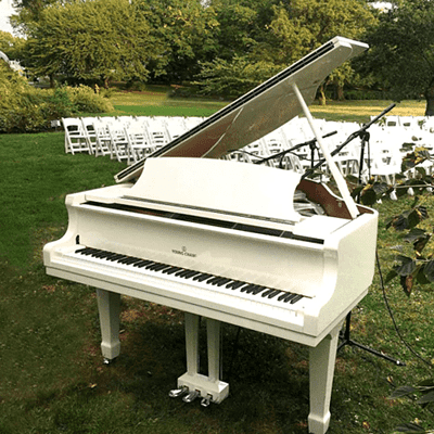 White rental piano outdoors setup for an event