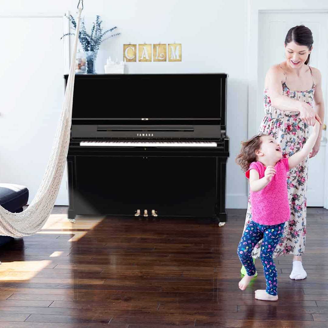 Mother and her child in the living room of an apartment with an upright rental piano